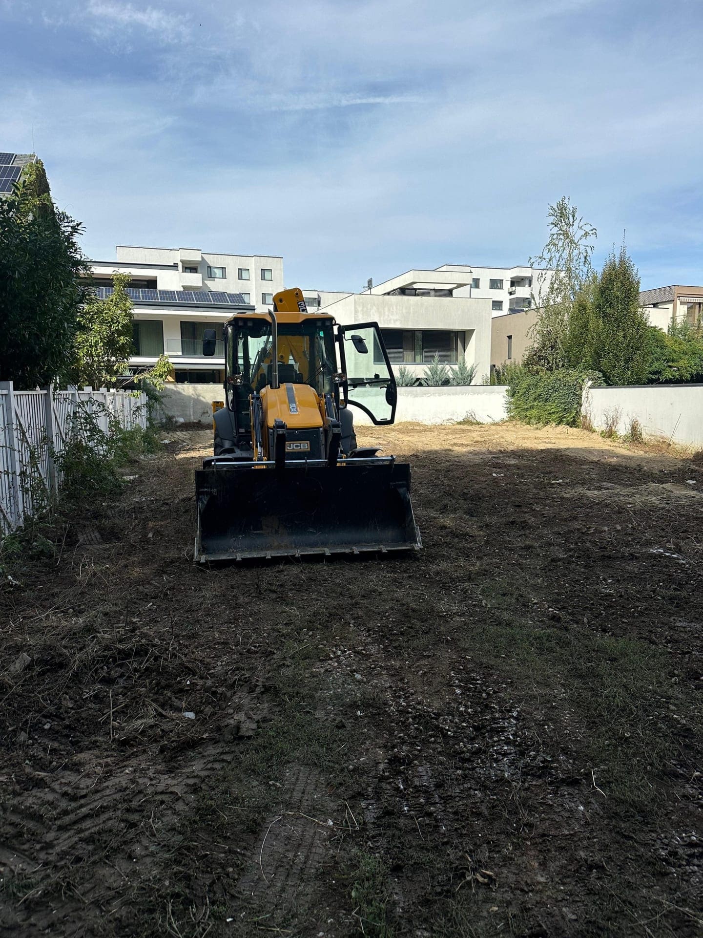 Buldoexcavator JCB pregătind și curățând terenul unui șantier rezidențial în București